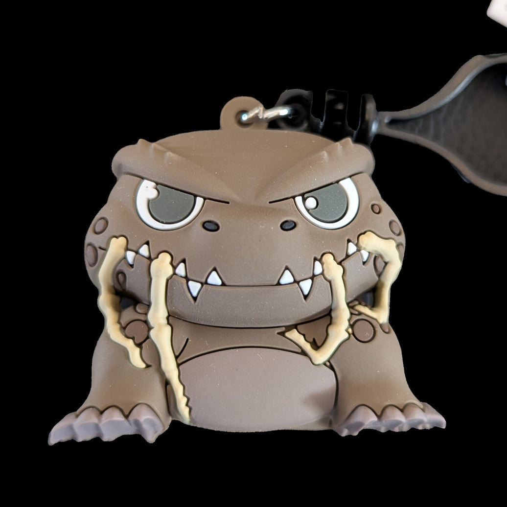Monogram Doug Godzilla-Kong 3D foam keychain featuring cartoon Godzilla with beige bone-like details on black background.
