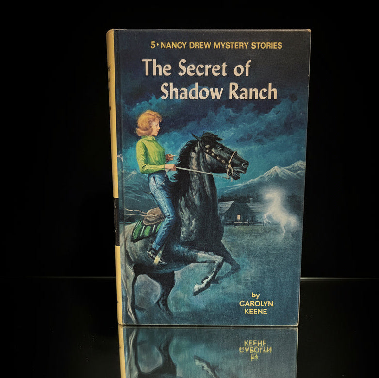 Vintage 1965 Grosset & Dunlap Nancy Drew book The Secret of Shadow Ranch by Carolyn Keene standing on black surface