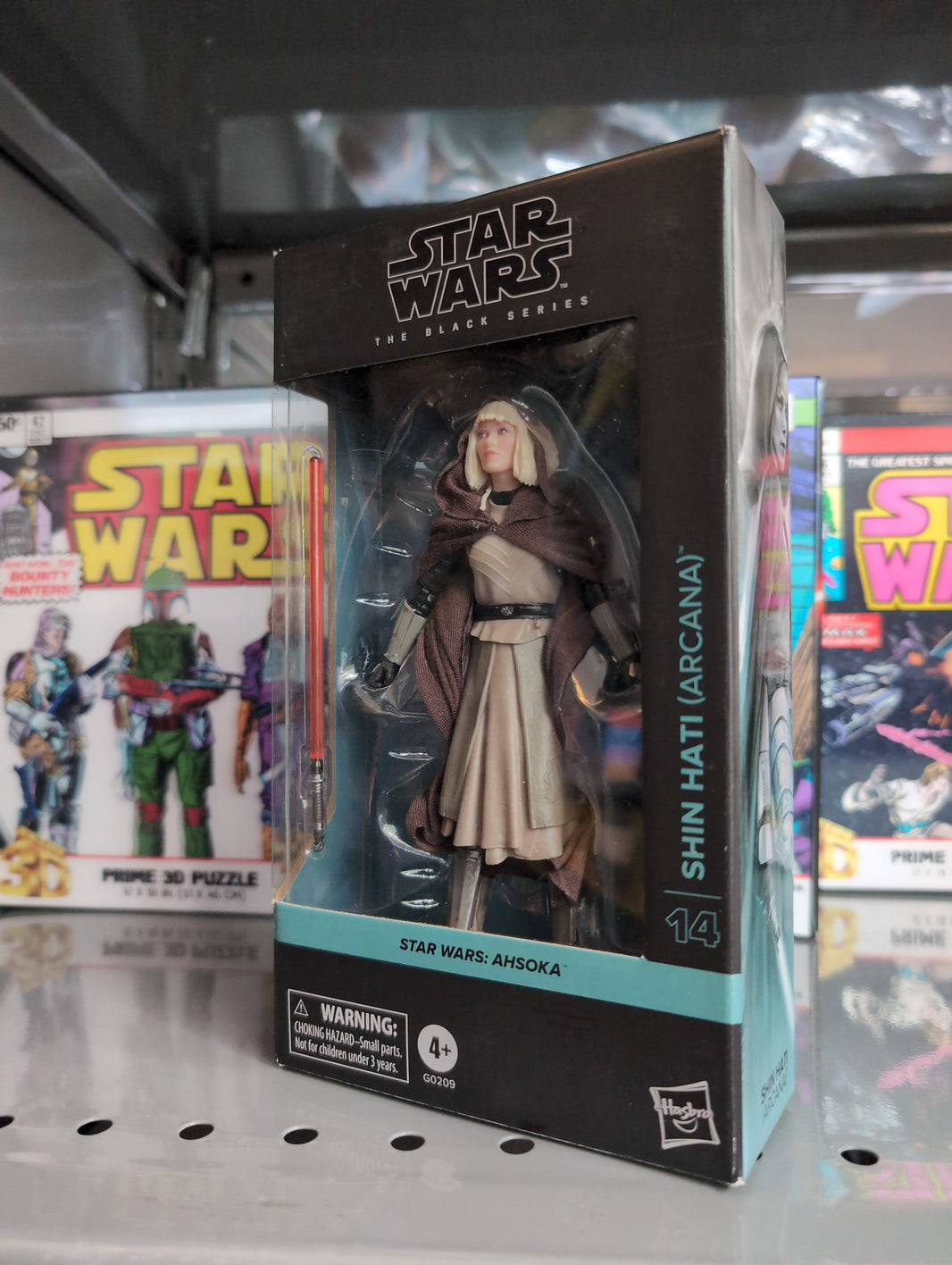 Hasbro Star Wars Black Series Shin Hati Arcana action figure in package with lightsaber accessory next to comics