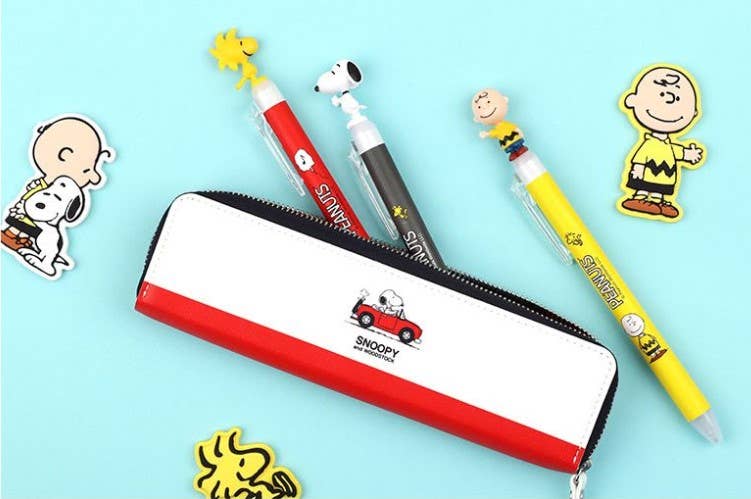K-Wonderland Peanuts ballpoint pens in red, black, and yellow with Snoopy, Woodstock, and Charlie Brown figure toppers and case
