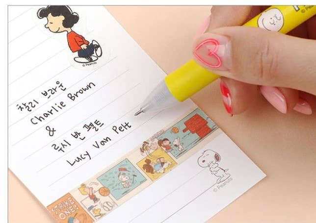 K-Wonderland Peanuts ballpoint pen in yellow with Snoopy character topper writing on decorated paper