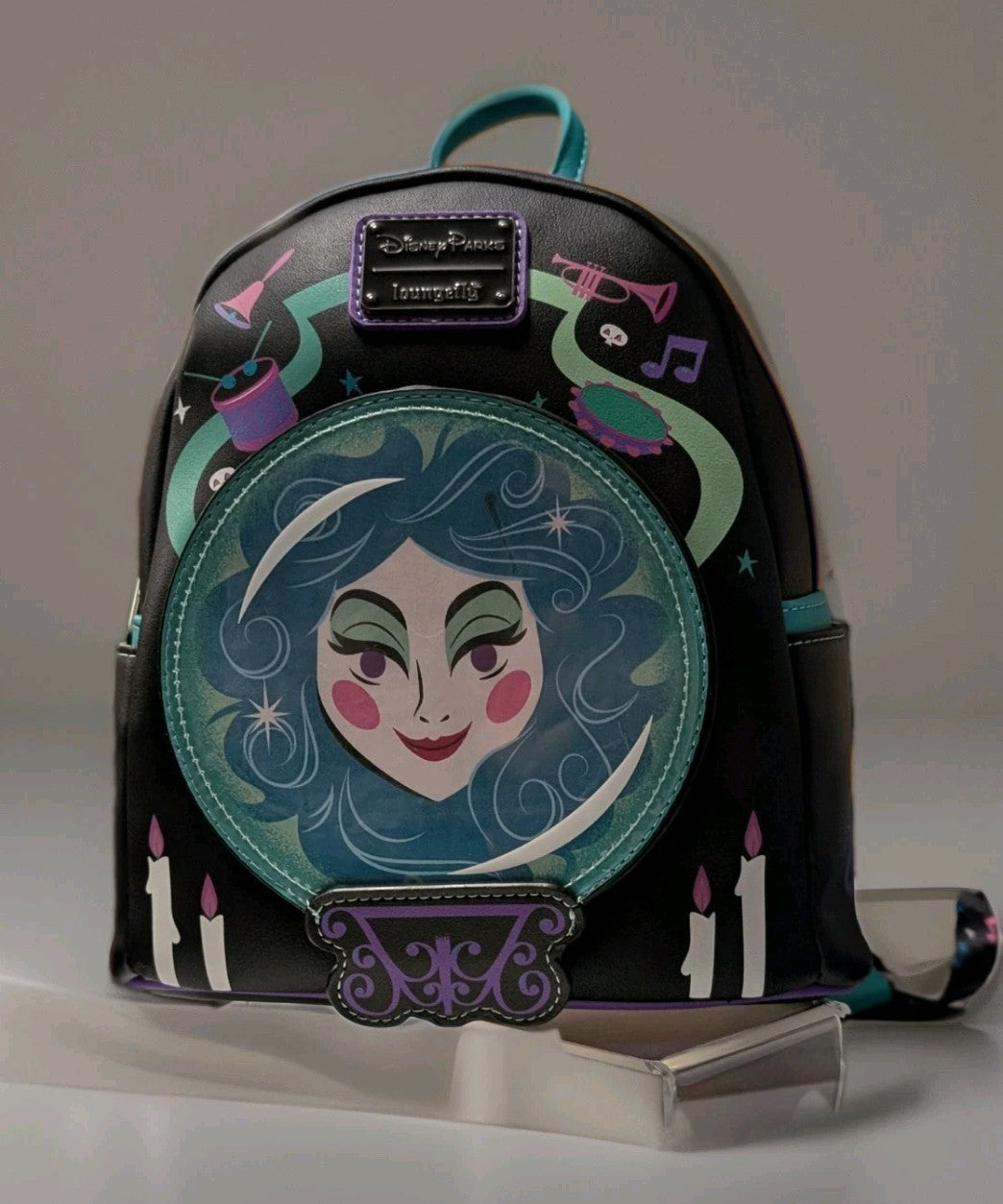 Loungefly mini backpack with Haunted Mansion Madame Leota design, teal accents, candles, and musical instruments on black faux leather