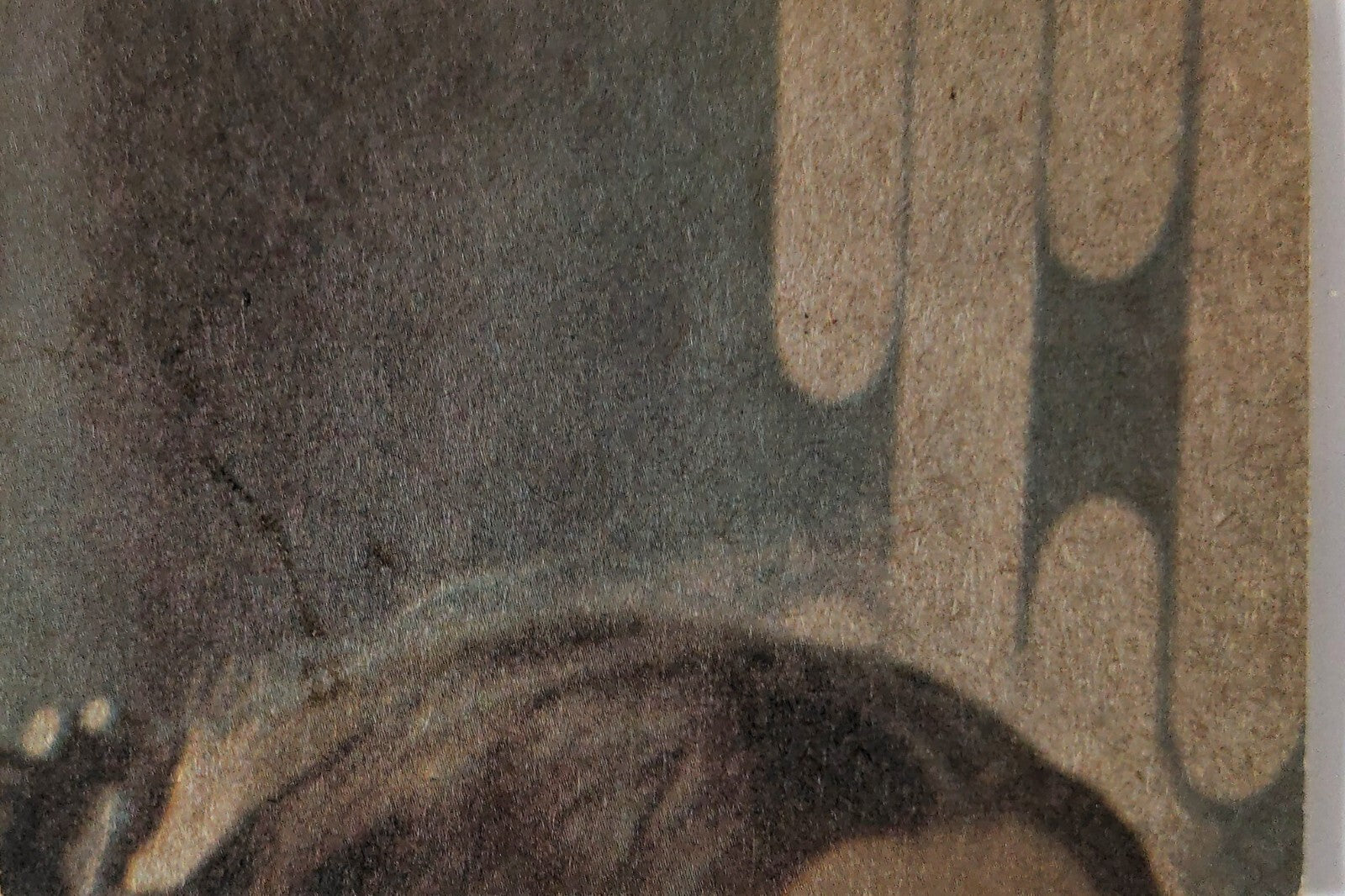 Close-up of vintage book cover showing textured background and part of illustration with muted tones