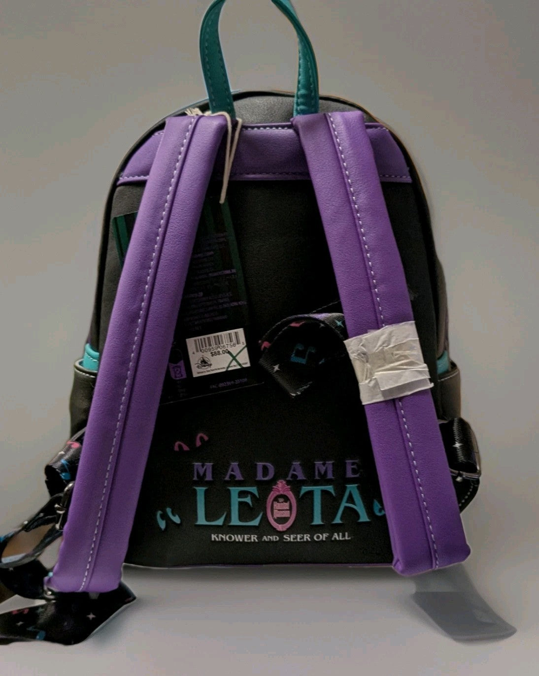 Loungefly mini backpack back view with purple straps and teal handle featuring Madame Leota inspired design on black faux leather