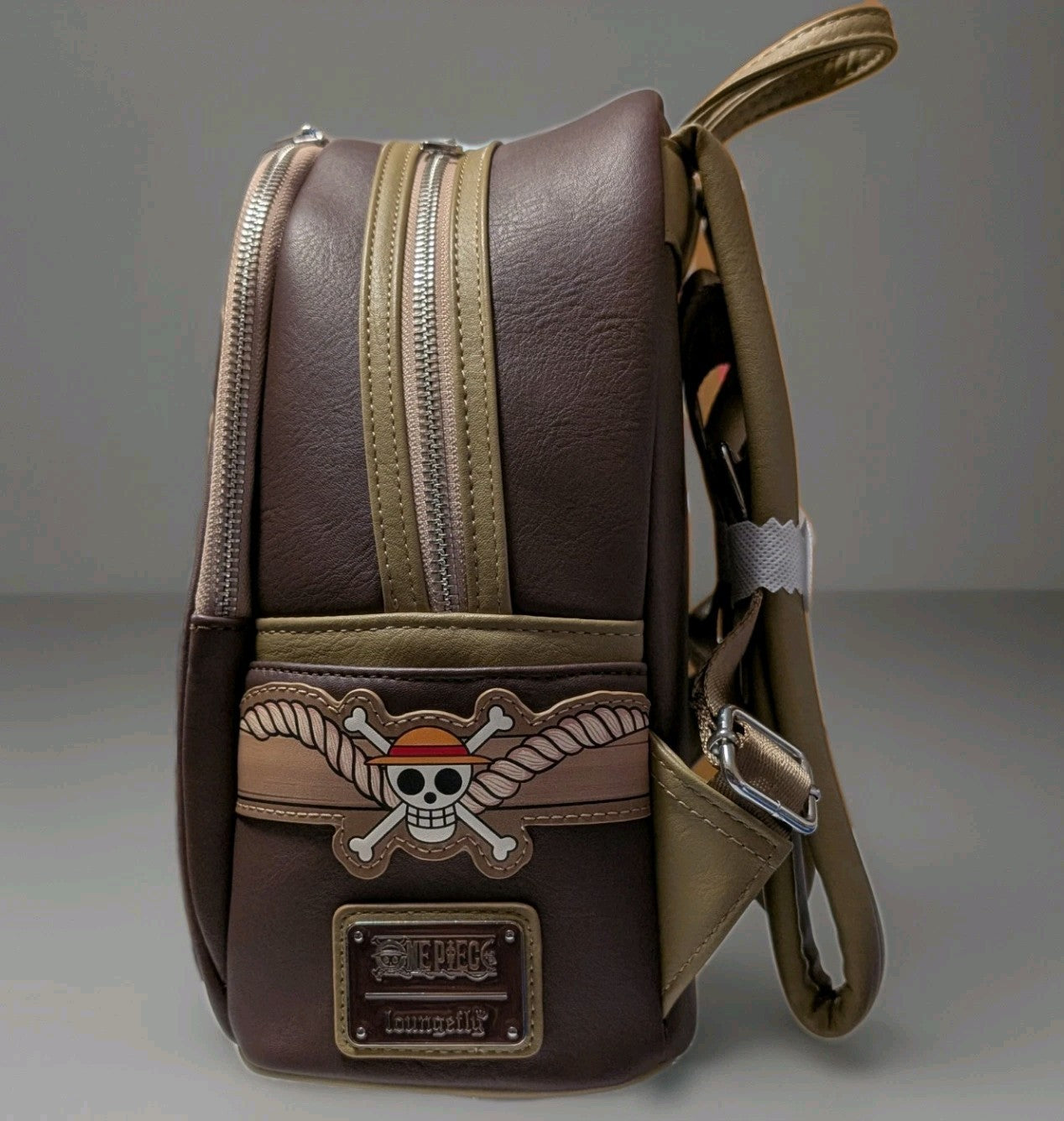 Side perspective of Loungefly mini backpack with Monkey D. Luffy skull and crossbones emblem on brown faux leather