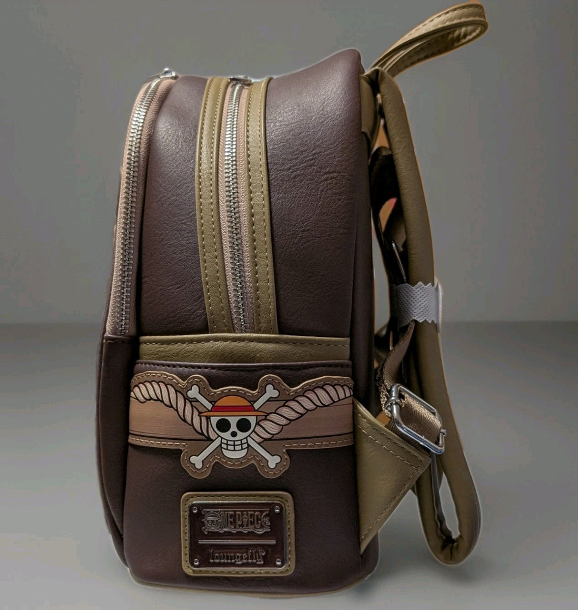 Side perspective of Loungefly mini backpack with Monkey D. Luffy skull and crossbones emblem on brown faux leather