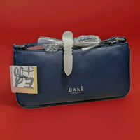 Danielle navy blue crossbody purse with silver buckle and Disney tag against red background