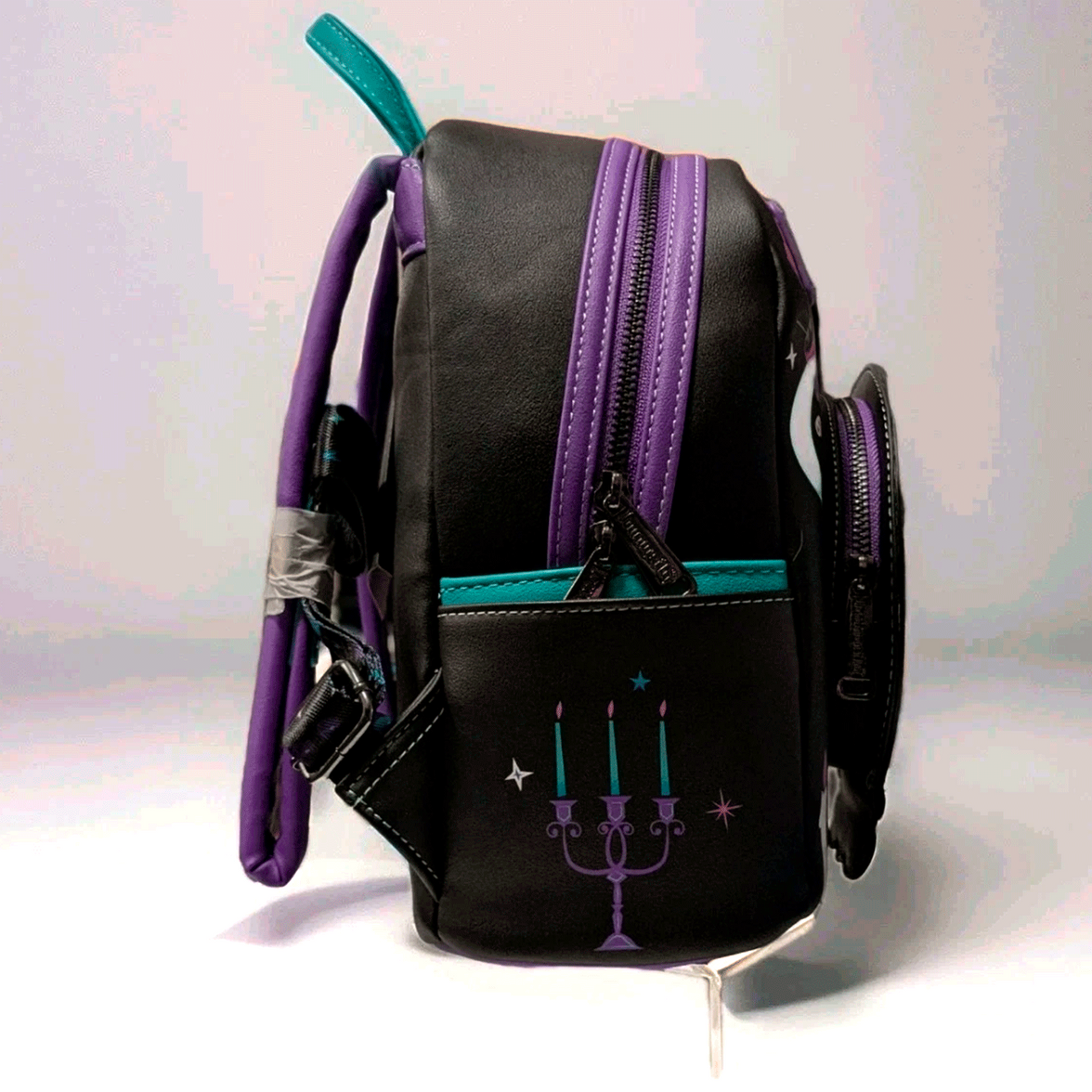 Loungefly mini backpack side view featuring Haunted Mansion inspired black faux leather with purple and teal accents and candelabra design