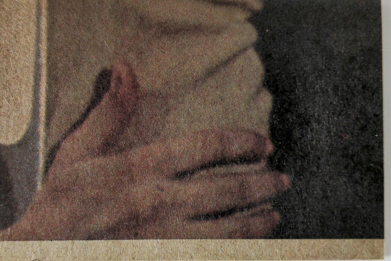 Close-up of hands gently clasping a textured surface with muted, earthy tones and soft shadows