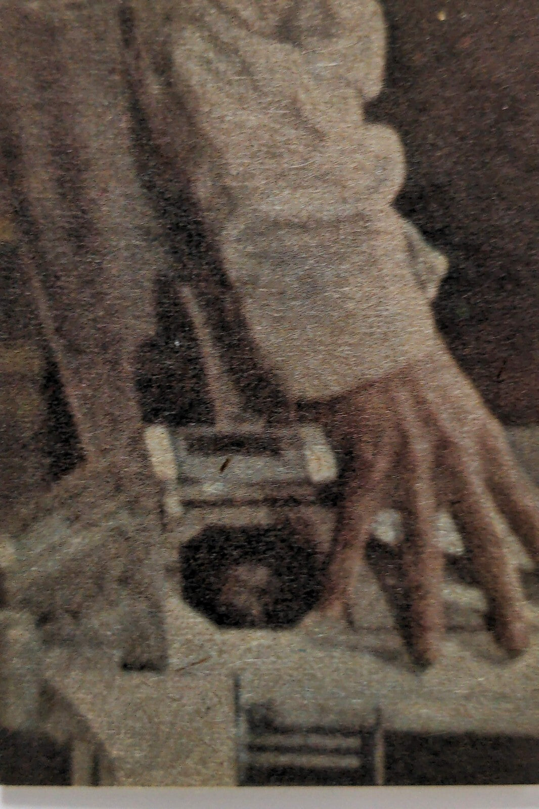 Close-up of hand reaching over table with miniature car and architectural model details in muted tones