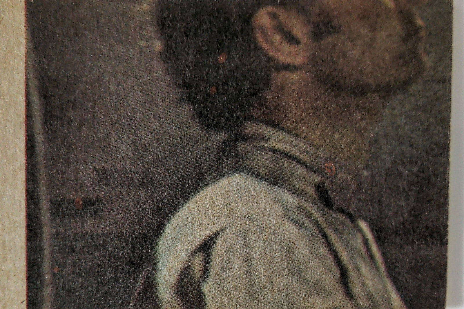 Close-up of vintage book cover featuring a man in profile wearing a white shirt against dark background
