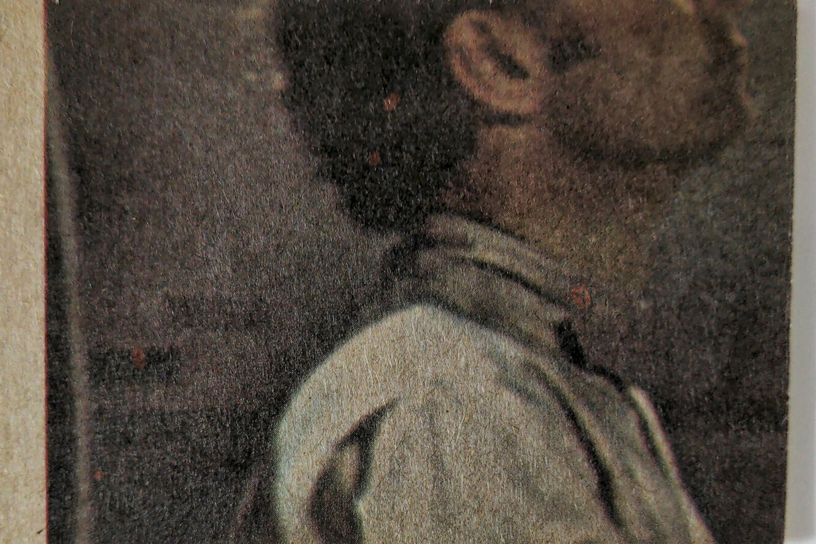 Close-up of vintage book cover featuring a man in profile wearing a white shirt against dark background