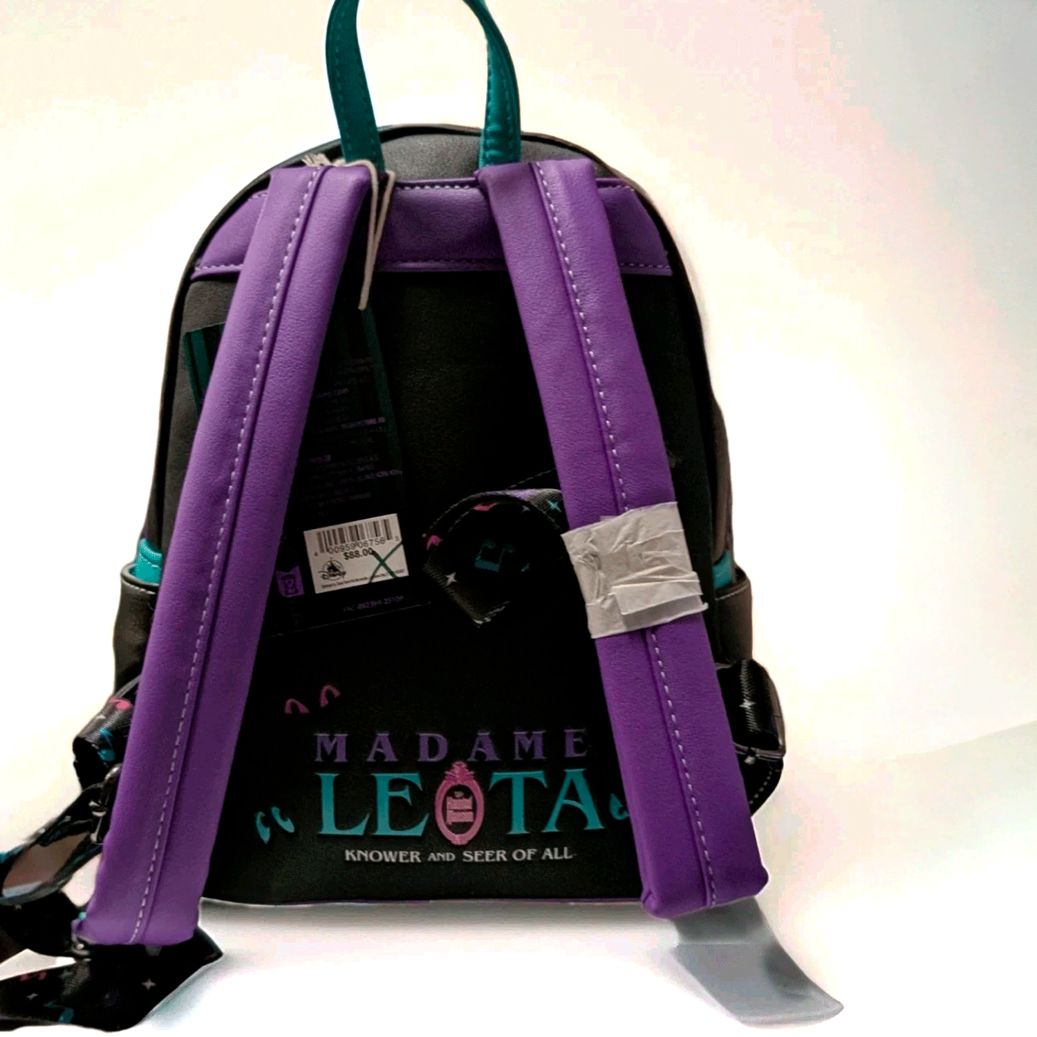 Loungefly mini backpack featuring Madame Leota theme with purple straps and teal accents on black background back view