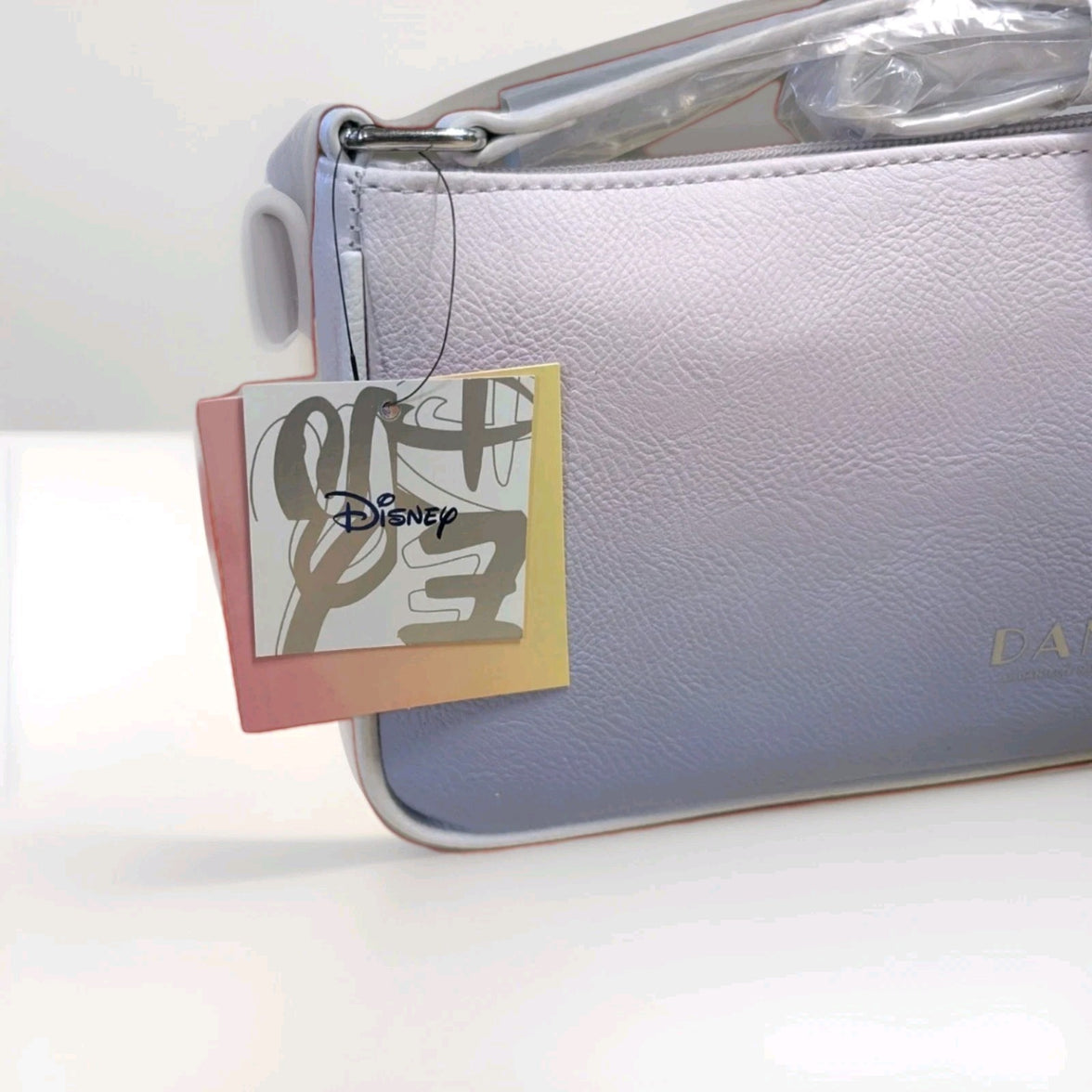 Danielle Nicole pastel gradient baguette bag with Disney logo tag and soft textured faux leather close-up view