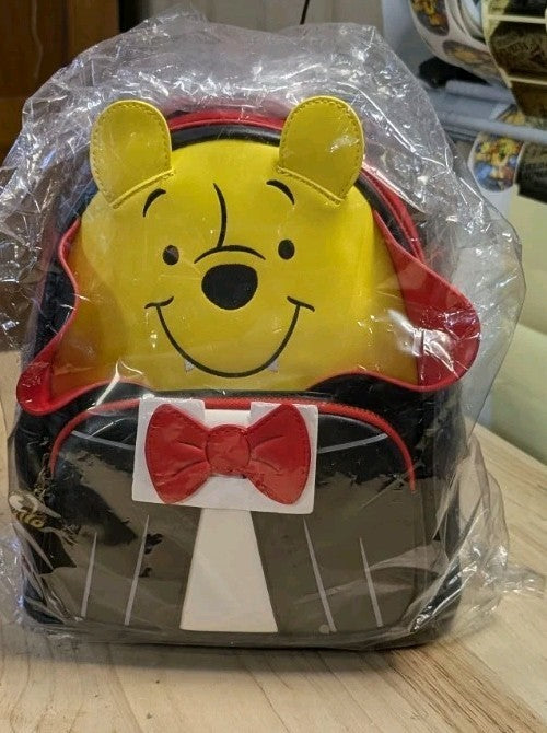 Loungefly mini backpack showing Winnie the Pooh in vampire cosplay with red bow tie and black cape details wrapped in plastic
