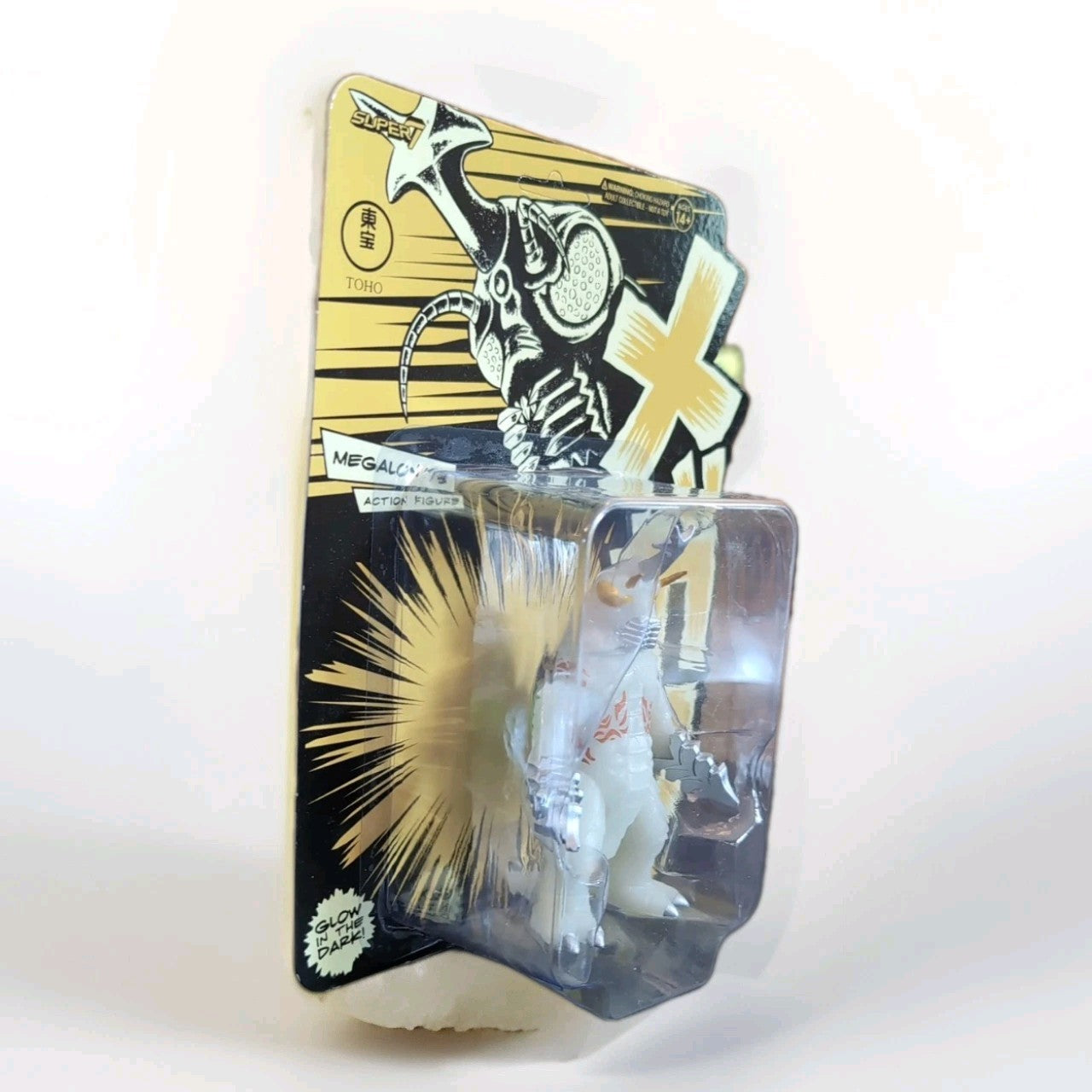 Super7 rare Megalon 1973 glow-in-the-dark figure in sealed vintage packaging with bold graphic design background