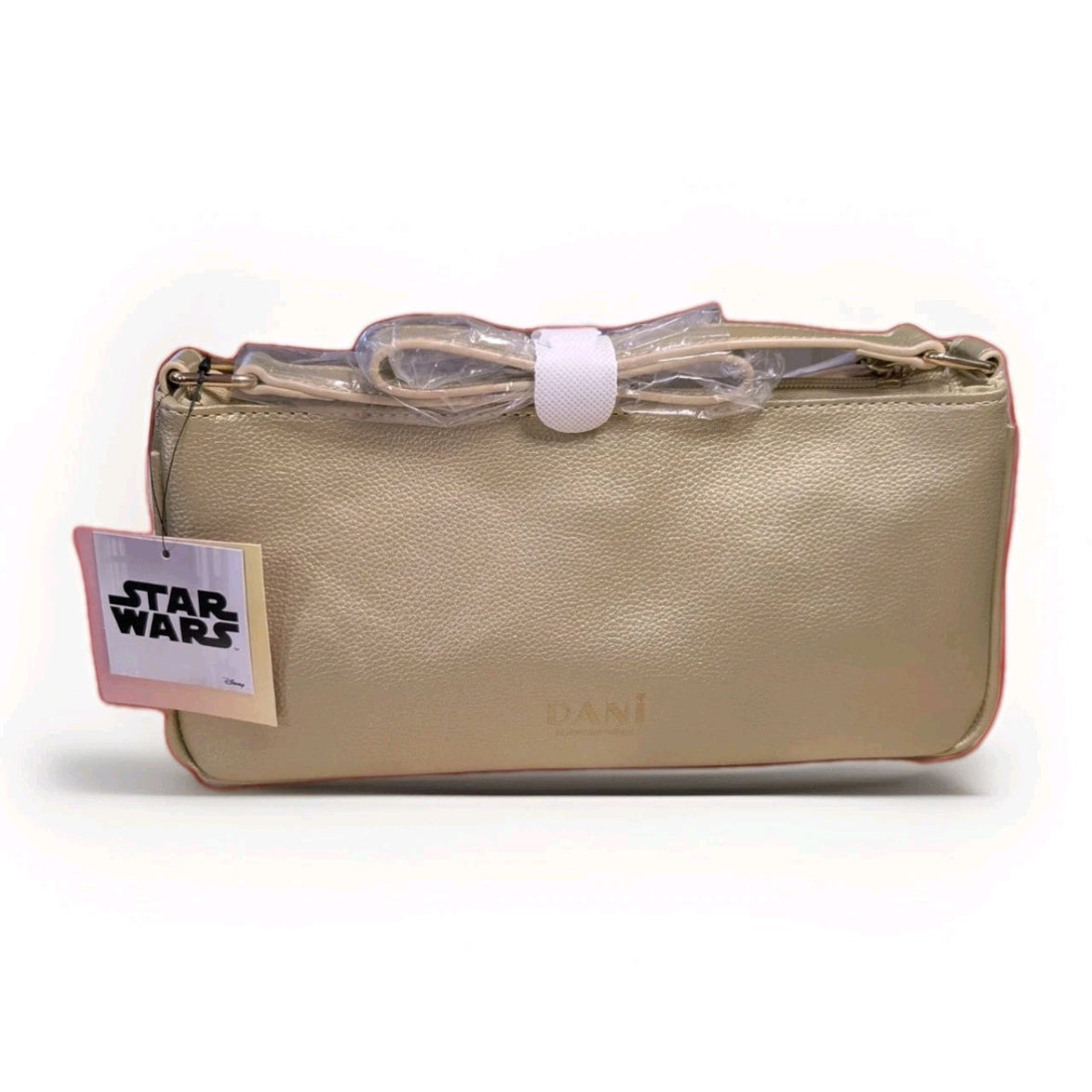 Beige Danielle Nicole crossbody bag with Star Wars tag featuring textured faux leather and wrapped strap against white background