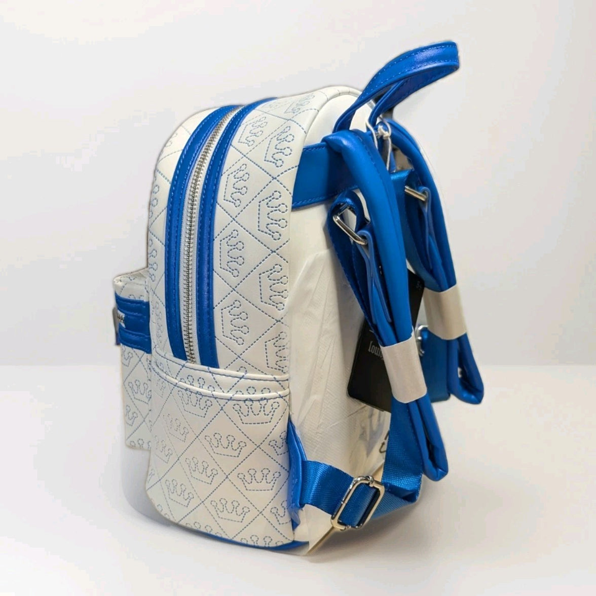 Loungefly mini backpack in white vegan leather with blue crown patterns and adjustable blue straps side angle view