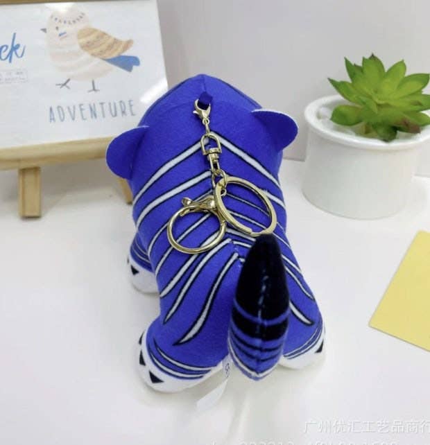 K-Wonderland plush tiger keyring in rich blue with white stripes and gold clasp displayed on white surface with decor background