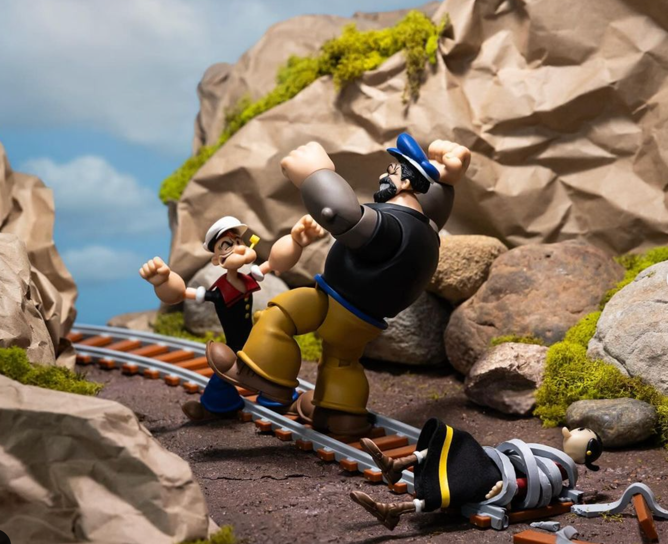 Boss Fight Studio Llc dynamic Bluto and Popeye figures in fight scene on rocky railroad track with Swee’Pea figure nearby