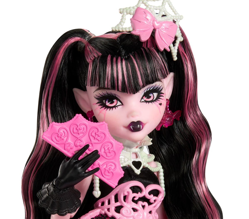 Mattel Monster High Draculaura doll with pink and black hair wearing party attire and holding pink birthday cards