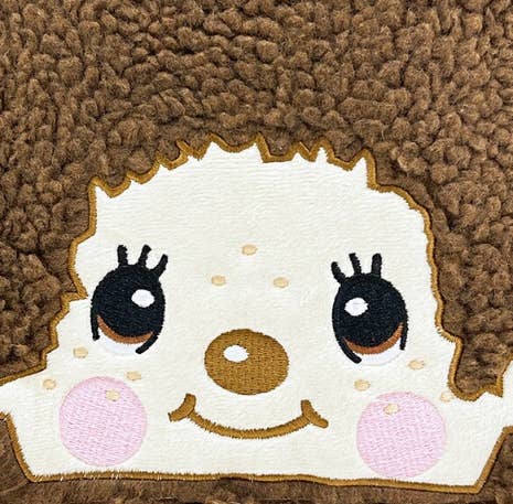 Close-up of K-Wonderland Monchhichi lunch bag featuring embroidered character face on plush brown teddy fleece background