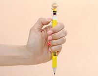 K-Wonderland Peanuts ballpoint pen in yellow with detailed Charlie Brown figure topper held in hand on plain background