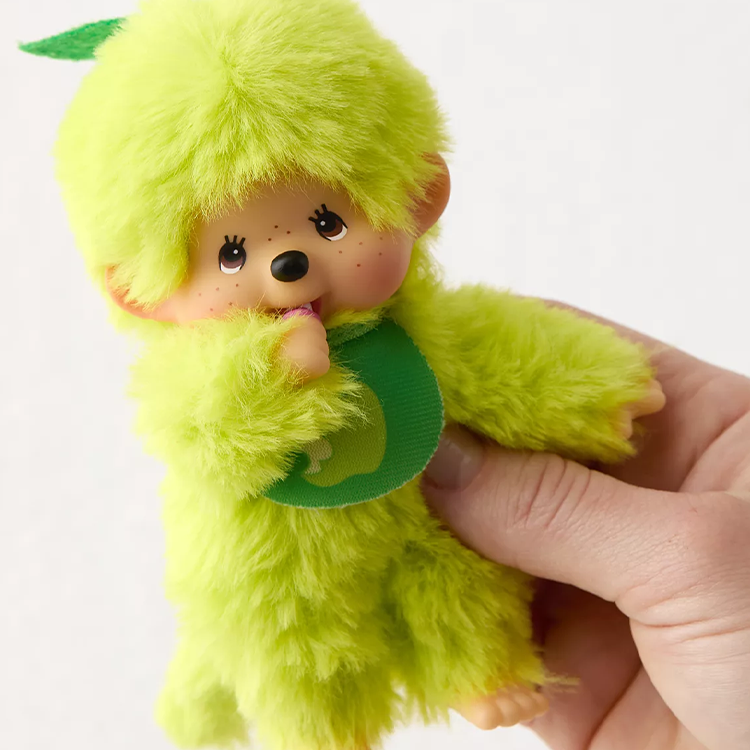 Sekiguchi Monchhichi 5-inch plush in apple green with soft fur, plastic face, hands, and feet held in hand.