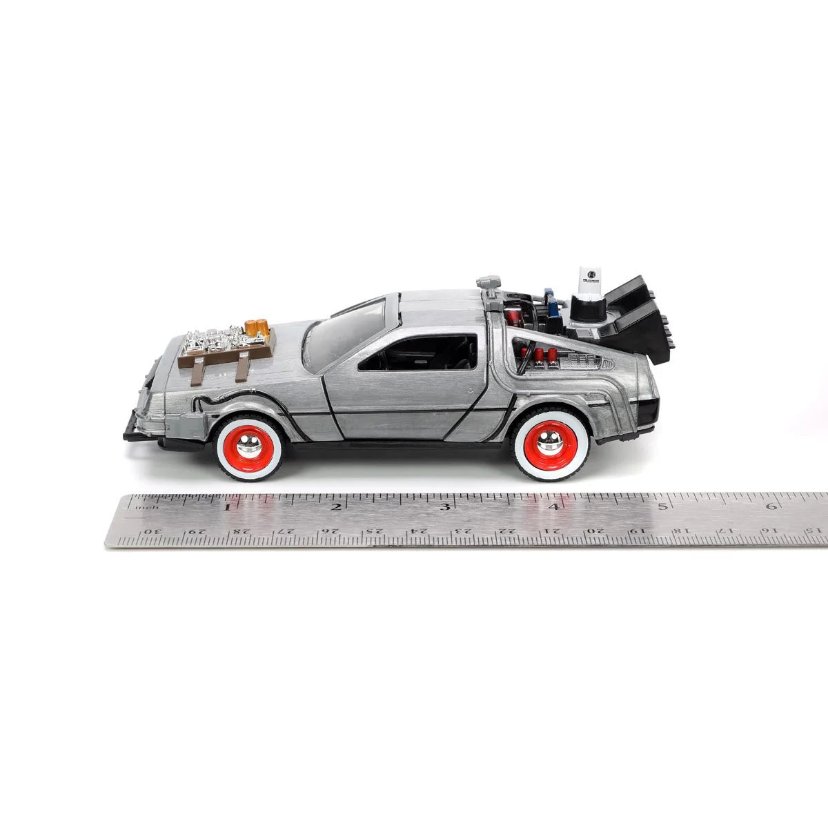 Ruler showing scale beneath a silver DeLorean-style toy car with red wheels