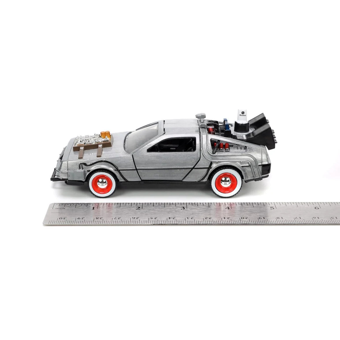 Ruler showing scale beneath a silver DeLorean-style toy car with red wheels