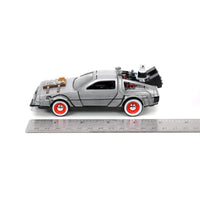 Ruler showing scale beneath a silver DeLorean-style toy car with red wheels