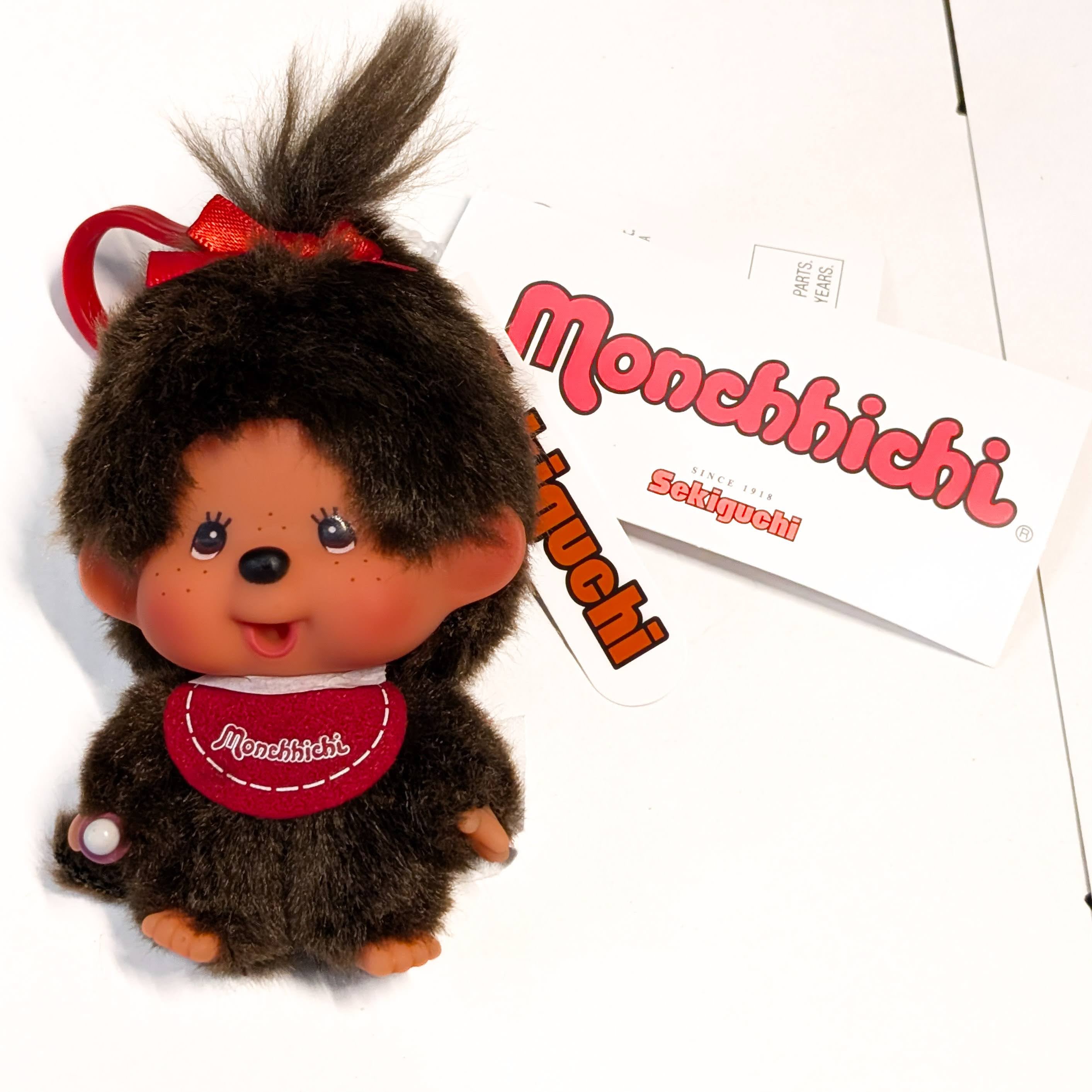 Sekiguchi Monchhichi Classic Big Head Girl plush keychain with red bow and original branded hang tags visible