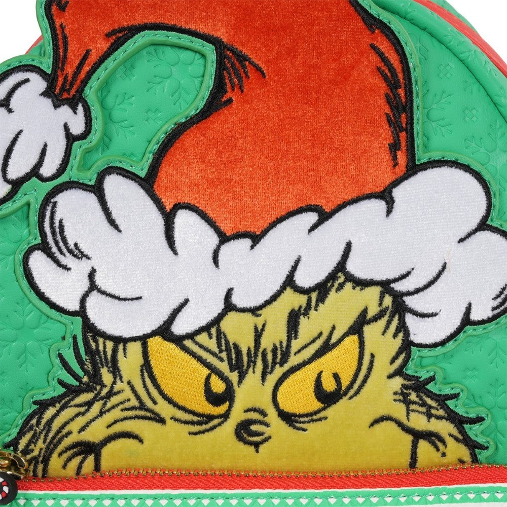 Close-up of Loungefly mini-backpack featuring the Grinch wearing a Santa hat on green textured background