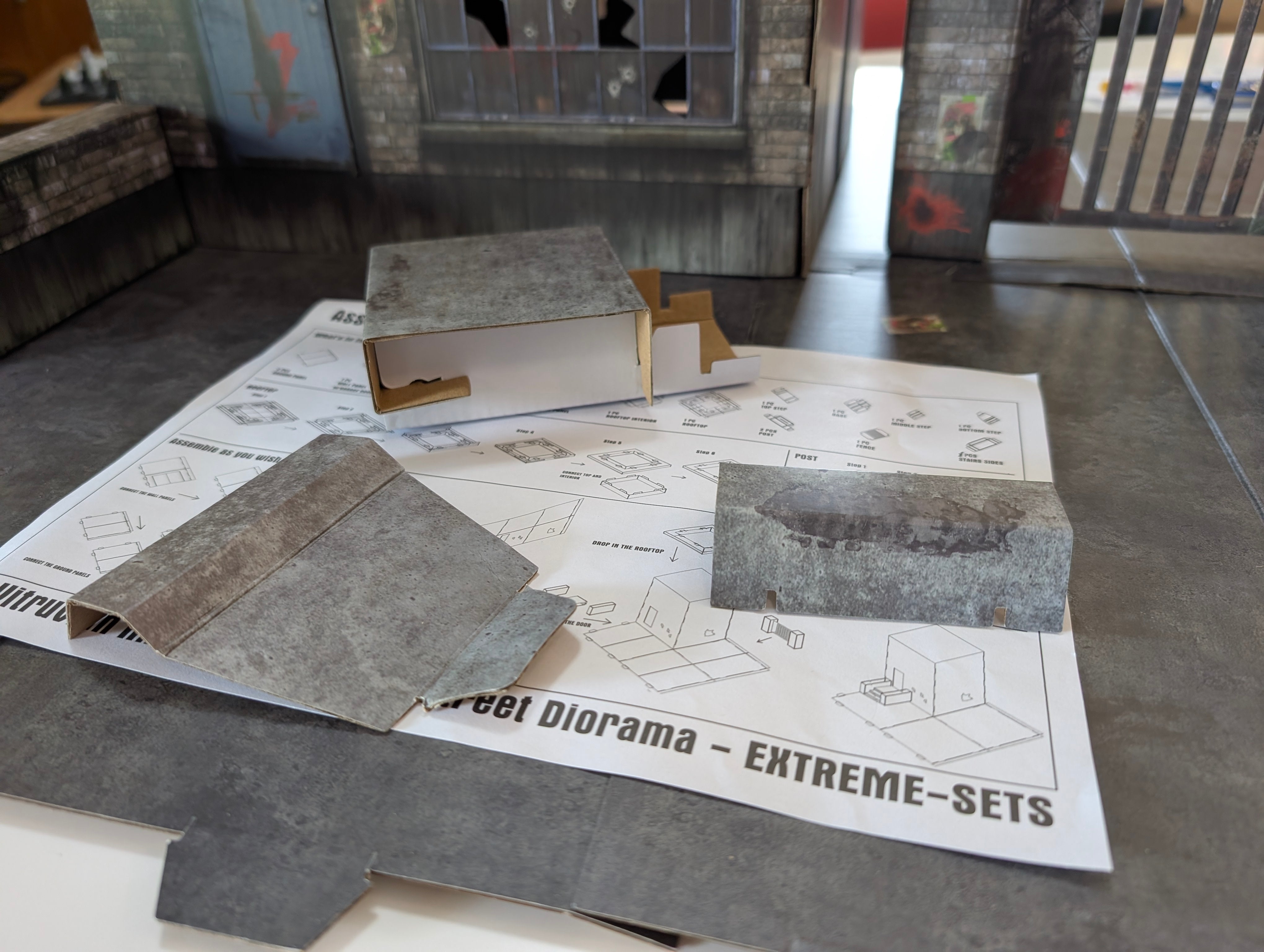 Parts of Vitruvian H.A.C.K.S. Series Z Zombie Diorama 1/18 Scale Street by Boss Fight Studio Llc laid out on assembly instructions