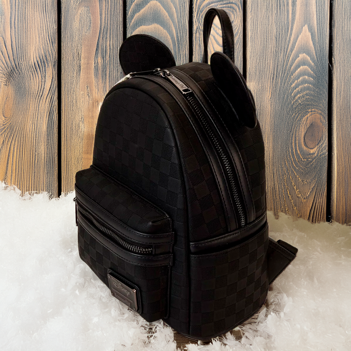 Loungefly Disney Mickey Ear mini backpack in black checkerboard pattern with ears and front zip pocket on snow background