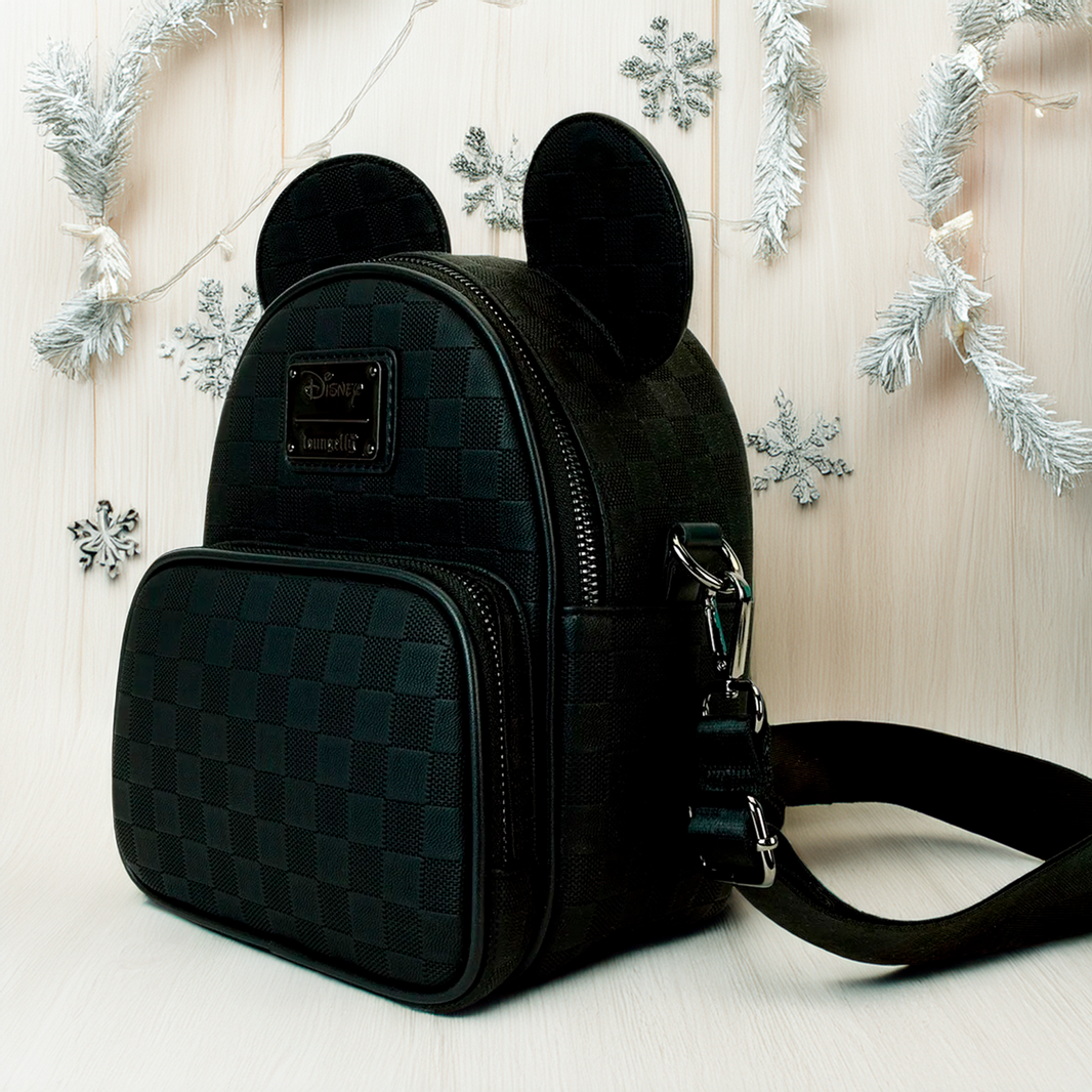 Loungefly Disney Mickey Ear checkerboard mini convertible crossbody backpack with front pocket and zipper closure on light wood background