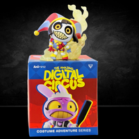 Small jester figure with glowing eyes and mischievous grin standing atop colorful Digital Circus collectible box.