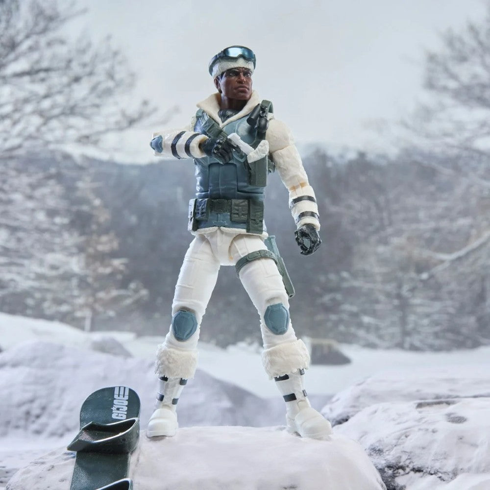 Action figure in white winter gear standing in a snowy landscape beside a snowboard