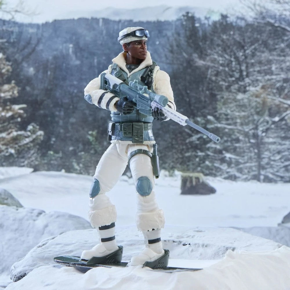Action figure in white winter gear holding a rifle while standing on skis in a snowy mountain landscape