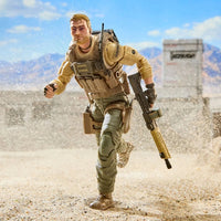 Bearded soldier action figure running across a sandy desert landscape with a rifle and tactical gear