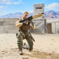 Action figure soldier kneeling with a rifle in a desert military compound