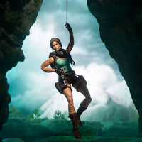 Female adventurer action figure hanging from a rope inside a rocky cave