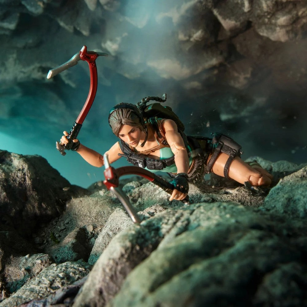 Female adventurer climbing rocky terrain while holding two ice axes