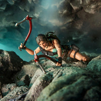 Female adventurer climbing rocky terrain while holding two ice axes
