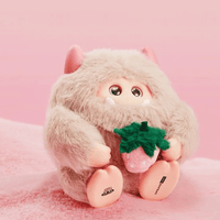OHKU Giggle Monster Marshmallow Dreams plush with cream fur holding a green strawberry on soft pink surface