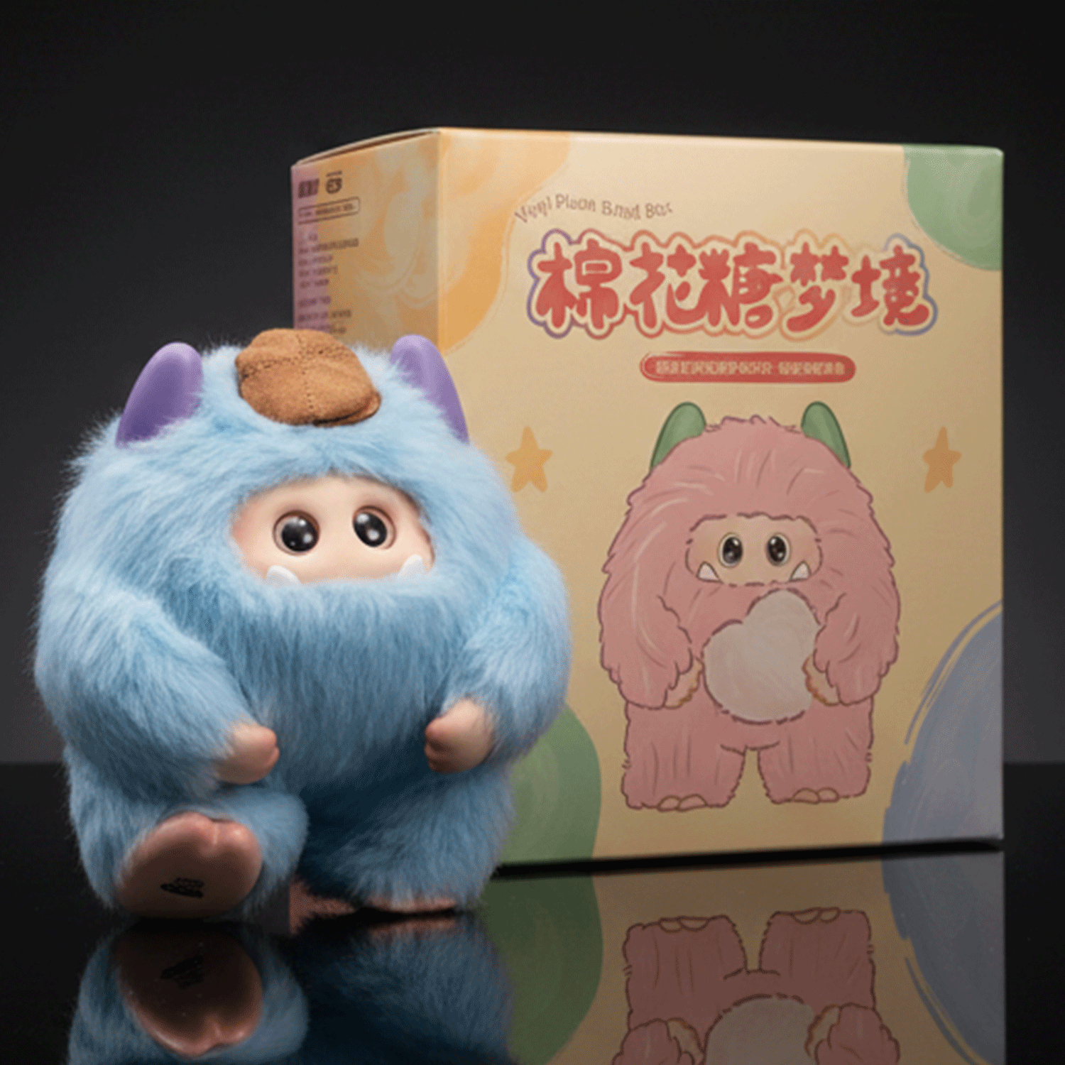 OHKU blue fluffy Giggle Monster Marshmallow Dreams vinyl plush with brown patch and big eyes beside illustrated box