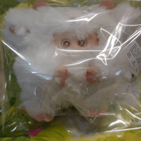 OHKU Giggle Monster vinyl plush with large eyes and fluffy white fur, inside clear plastic blind box packaging