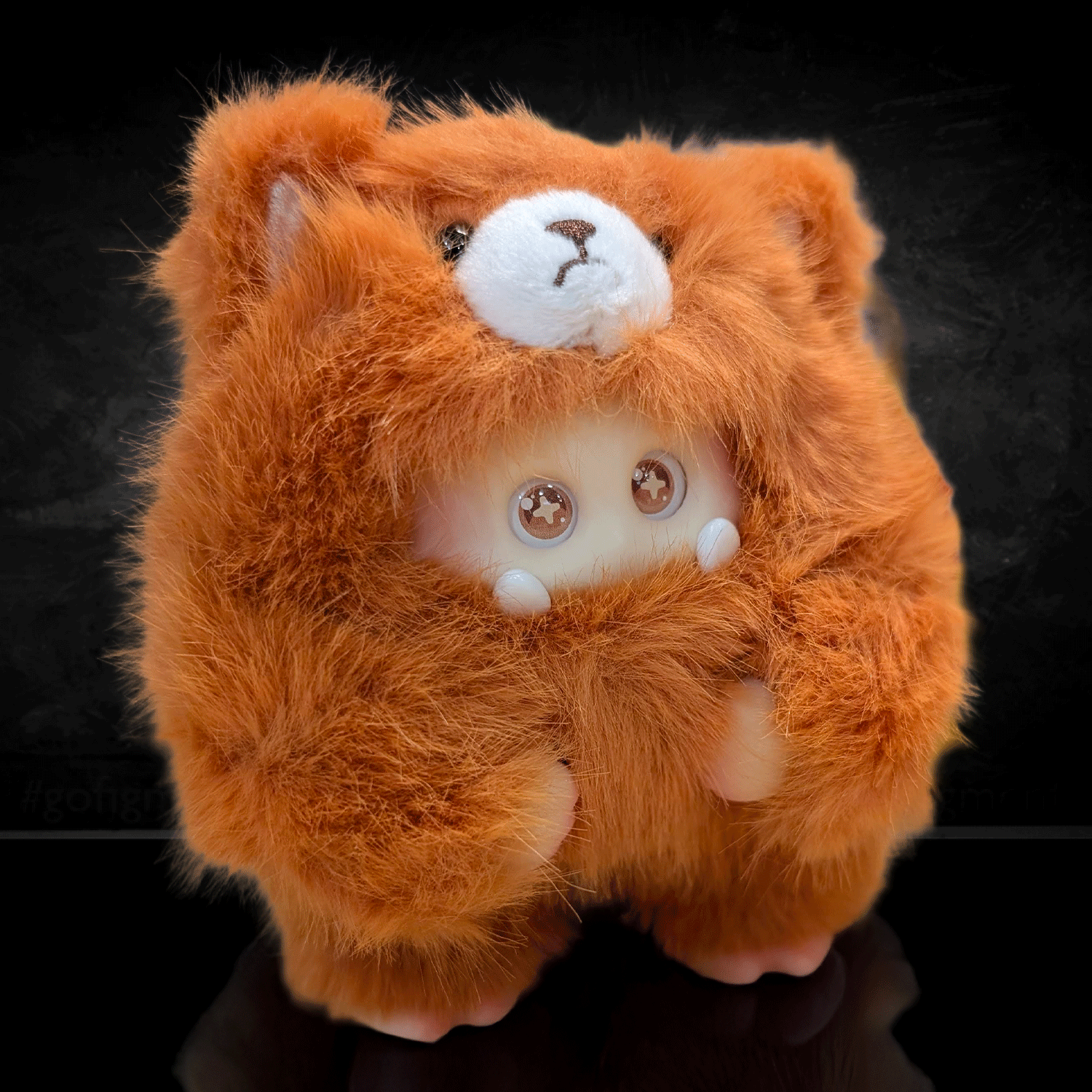 OHKU Giggle Monster vinyl plush in fluffy bright orange bear-inspired costume with sparkling eyes on black background