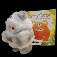 OHKU Giggle Monster plush in fluffy gray and white creature costume with expressive eyes next to Furry Forest blind box packaging