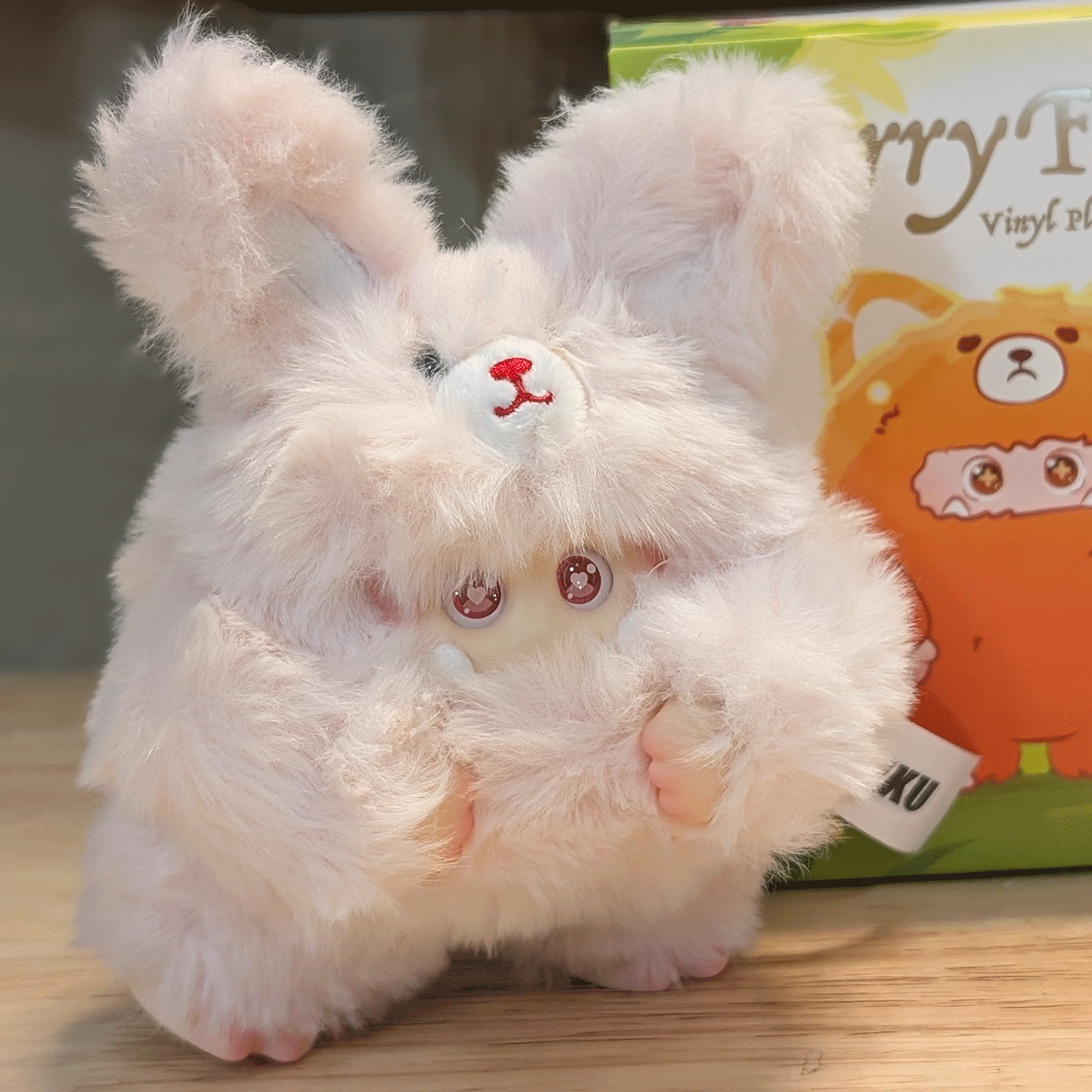 OHKU Giggle Monster Furry Forest plush figure in fluffy pink bunny costume with expressive eyes on wooden surface